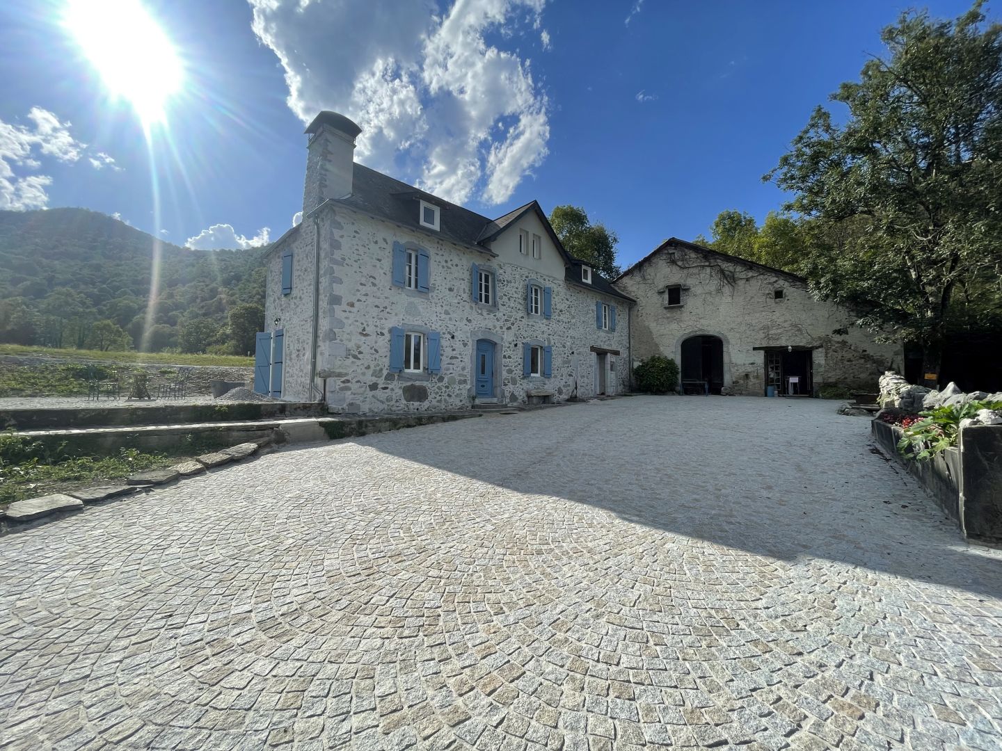 La maison béarnaise en pierre du Val Éveillé et sa grange, aux volets bleus, au pied des Pyrénées à Arudy