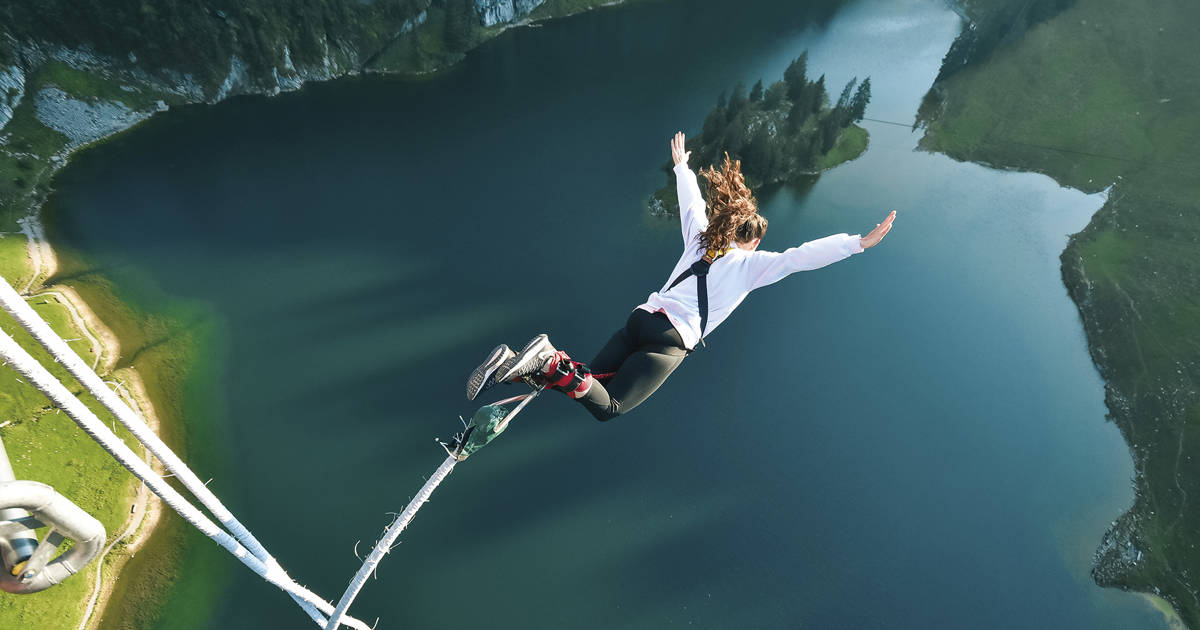 Saut à l’élastique vu du haut, plongeant sur un lac turquoise entouré de montagnes